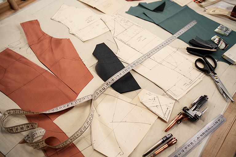 Paper gown pattern pieces and measuring tape spread across a cutting table