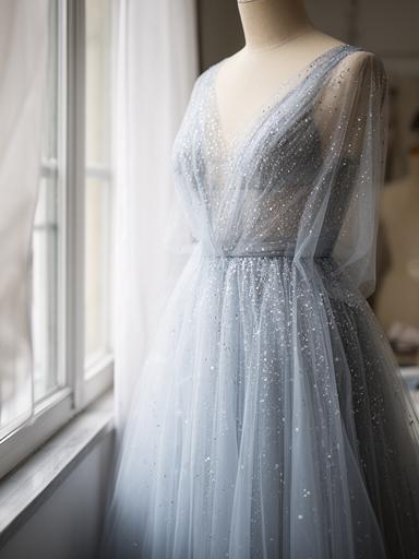 Anonymised pale blue tulle dress with scattered beadwork photographed beside an atelier window